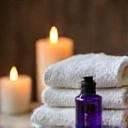 Scena di relax con il flacone di olio essenziale di lavanda, candele e asciugamani bianchi.